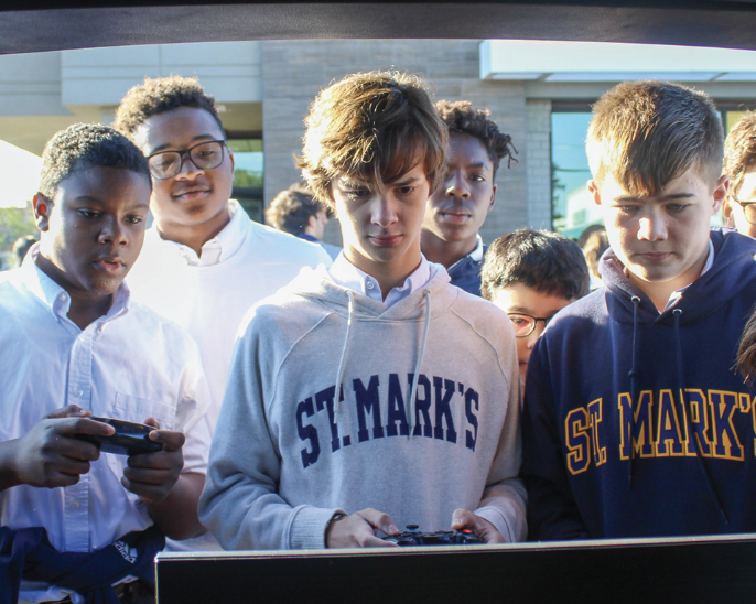 Freshmen students partake in an intense game of FIFA on an XBox set up out of the back of a car on all-day day during McDonald’s Week in the restaurant’s parking lot.
